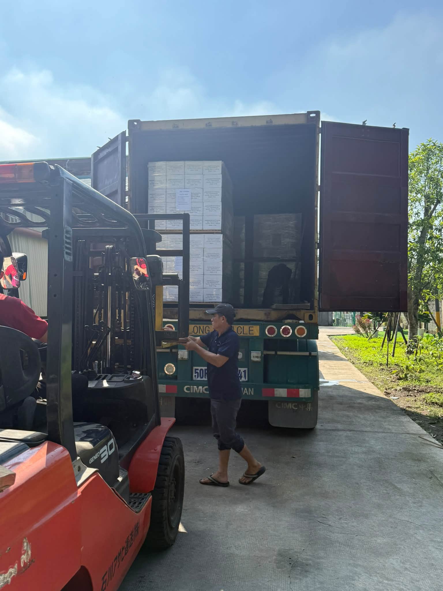 Xe nâng đưa kiện sàn gỗ sồi vào container, công nhân hỗ trợ